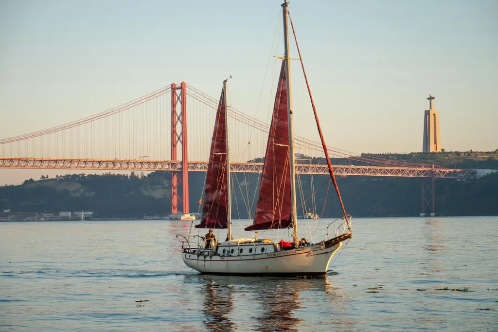 Sailing boat on the Tagus at sunset with the 25 de Abril Bridge